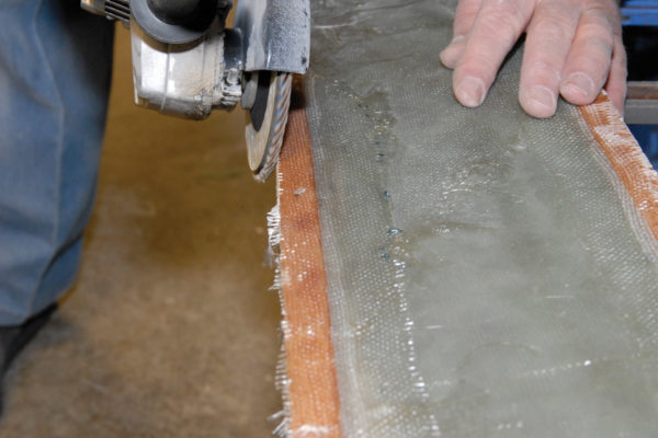 Trim the excess fiberglass off the mold with a body grinder. Then apply several coats of automotive paste wax on the molding surface. Any sticky spots will adhere to your layup and are likely to ruin both the part you’re making and the mold as well.