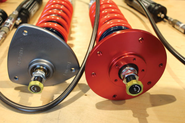 The strut tops on these Motion Control Suspension units differ for front and rear installation. The rebound resistance adjustment knobs are on top.