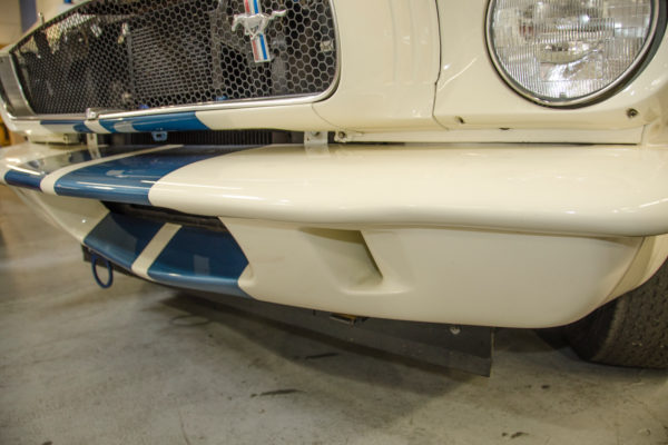 Peter Brock’s new front fascia for the Original Venice Crew’s revised GT350 was
designed to enhance the appearance of the Mustang’s front end, all while giving it a
distinctive appearance over the 1960s-era Shelby GT350. This revised front incorporates the stock front bumper but is made of composite material to reduce weight.
Note the brake scoops are now rectangular in shape, rather than round, and send air
directly to the front brakes. The flexible rubber air dam mounted underneath creates
high pressure in front of the radiator and low pressure behind to aid cooling. This
device eliminates the need for a vulnerable, low-hanging air-dam at the front, which
would not have a production appearance.